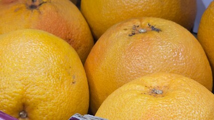 Whole grapefruits with textured peel in market setting. Perfect for fruit, citrus, grocery, and healthy lifestyle topics.
