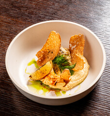 A beautifully presented dish showcases creamy hummus topped with crisp textures and vibrant greens