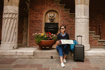 Tourist reading map while relaxing on steps in krakow old town