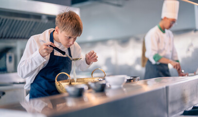 Senior male chef teaches young teenage boys cooking in school kitchen. Education Concept