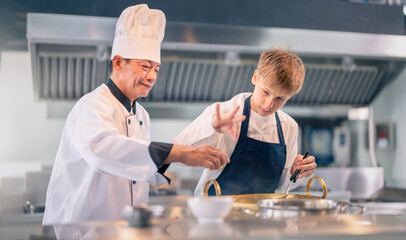 Senior male chef teaches young teenage boys cooking in school kitchen. Education Concept