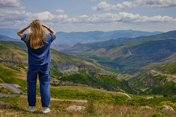 Woman standing on a mountain peak with arms outstretched, enjoying a breathtaking panoramic view of...