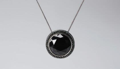 Elegant black gemstone pendant necklace with ornate silver setting, hanging against a plain white background.