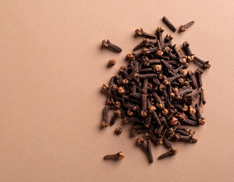 Whole cloves (laung) arranged in a small heap on a warm neutral background. Rich texture and minimal flat lay styling. Great for wellness, spice, cooking, and ayurvedic visuals.

