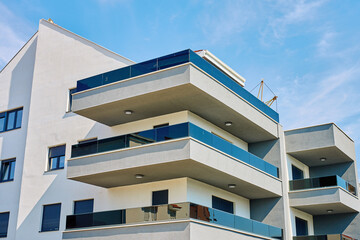 Modern apartment building with white facade, balconies and glass railings. Residential architecture with minimalist design