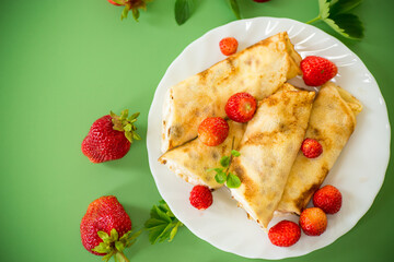 Pancakes with cottage cheese and strawberries on a green background