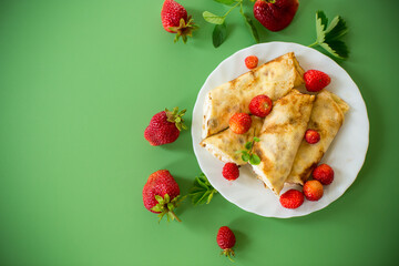 Appetizing pancakes with berries isolated on a green background