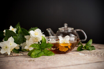 Fragrant tea with jasmine flowers in a glass cup on a black background
