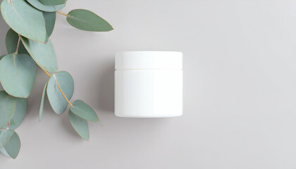 White jar and eucalyptus leaves on a light gray background.