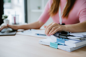 secretary is searching through pile of important documents on office table deliver them to manager for presentation in time at meeting. Concept of difficulty finding information from piles of document