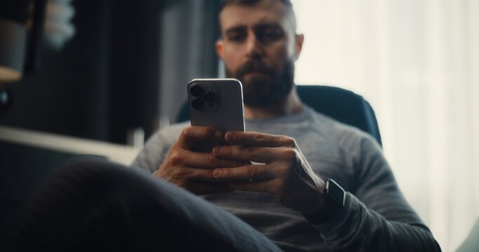 Financial Analyst Working on Smartphone, Analyzing Real-Time Stocks and Exchange Market Charts, Making Investments. Successful Businessman Works in Comfortable Office of Investment Bank. Dolly Shot. - Powered by Adobe