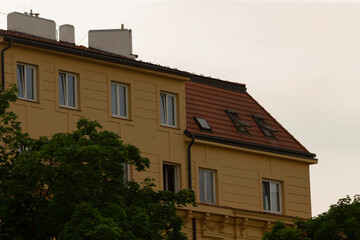 A beautifully designed twostory home with large windows for natural light and a stylish sloped roof, surrounded by lush greenery, exemplifies modern urban housing in a vibrant community