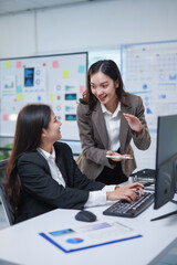 Two asian businesswomen are discussing and working together using desktop computer in modern office