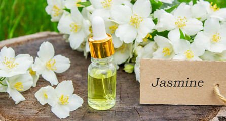 Jasmine essential oil in a glass bottle and jasmine flowers. Oils.