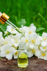 Jasmine essential oil in a glass bottle and jasmine flowers. Oils.