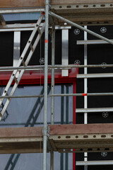 This image showcases scaffolding that is strategically supporting a ladder at a busy construction site, clearly displaying ongoing work on the exterior wall of the building