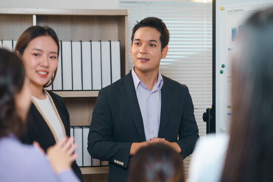 Asian businessman leading a team meeting, engaging in discussions and strategizing on work projects within a collaborative office environment