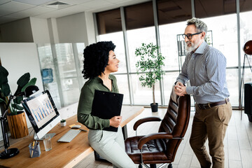 Professional business discussion between colleagues in a modern office workspace, emphasizing...