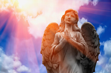 Ancient stone statue of beautiful angel in the rays of the sun. Horizontal image.