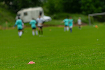A vibrant youth soccer practice session is taking place on a lush green grass field, featuring enthusiastic players wearing teal uniforms, and a goal proudly positioned in the background