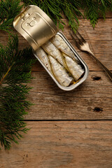Sardines in Tin on Rustic Wooden Table Surrounded by Greenery