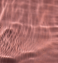 Mediterranean pink terracotta color plaster background with under water sun shadows.	