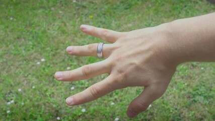 Showcasing Silver Ring On Ring Finger White Male Hand On Grass Backdrop