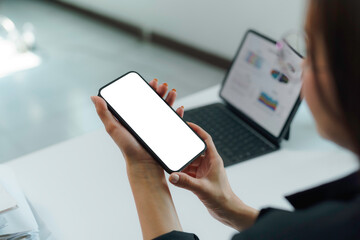 Businesswoman is using smartphone with white screen, working with tablet showing graphs and charts