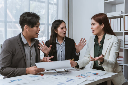 Asian businesspeople having an argument during a meeting, discussing financial charts and showing disagreement