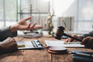 Judge holding a gavel while presiding over a legal discussion among lawyers in a courtroom setting,...