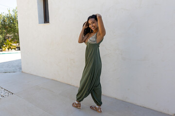 Latina model wearing green dress on white wall.