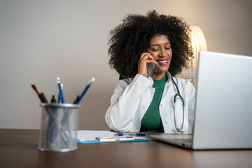 Female doctor talking with colleagues through a video call with a laptop in the consultation.