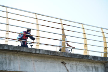 Two Children Walking on a Bridge with Bright Sky