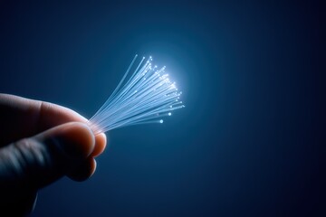 Fiber optic strands illuminated in a hand against a dark background showcasing technology and light