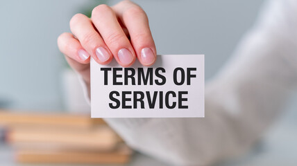 A person is holding a white card that says Terms of Service