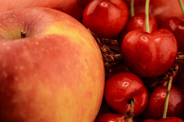 A vibrant red and yellow apple, ripe red cherries on a rustic wooden surface. the natural beauty and freshness of these popular fruits, perfect for themes of healthy eating and wholesome snacks