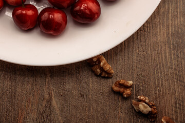 A tempting close-up of red cherries, with rustic walnuts scattered on a wooden surface. healthy snacking and natural goodness. for themes of wholesome food, delicious treats, and balanced nutrition