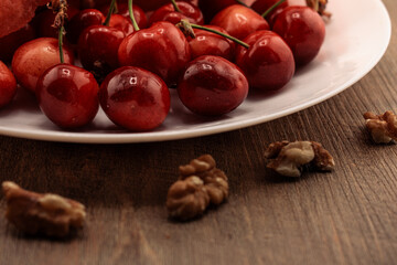 A tempting close-up of red cherries, with rustic walnuts scattered on a wooden surface. healthy snacking and natural goodness. for themes of wholesome food, delicious treats, and balanced nutrition