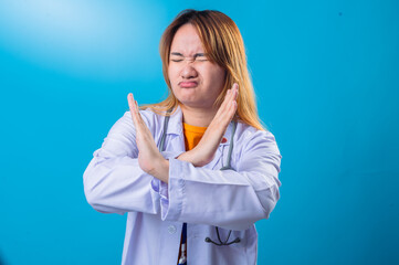 Serious Asian female doctor wearing white coat and orange shirt making crossed arms gesture in...
