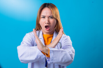 Serious Asian female doctor wearing white coat and orange shirt making crossed arms gesture in...