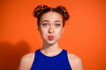 Playful Young Woman Making a Funny Face Against a Vibrant Orange Background While Dressed in Stylish Blue Casual Fashion