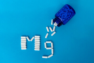 Blue bottle with white magnesium tablets that are spilling out and tablets lined with the Mg symbol...
