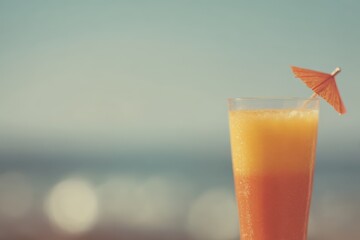 Colorful beach cocktail served with a mini umbrella against a shimmering ocean background on a sunny day