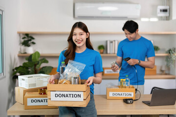 Charitable Giving. Volunteer presenting donation items with a joyful expression.