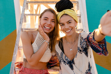 two stylish beautiful women relaxing having fun on beach in summer fashion trend outfit