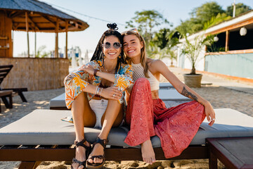 two stylish beautiful women relaxing having fun on beach in summer fashion trend outfit