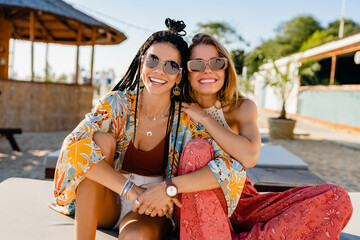 two stylish beautiful women relaxing having fun on beach in summer fashion trend outfit