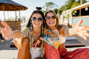 two stylish beautiful women relaxing having fun on beach in summer fashion trend outfit