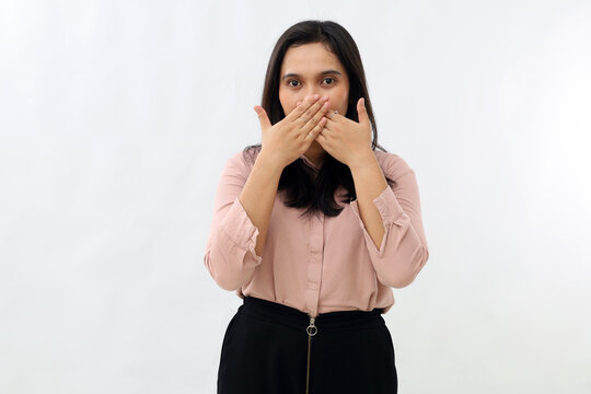 Shocked young Asian woman covering mouth and looking at camera, making mistake or embarrassment, forbidden to speak, a secret, wearing shirt, standing against white background.