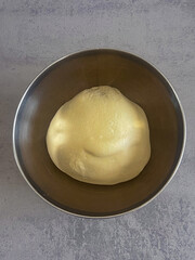 Smooth pizza dough resting in bowl, ready for homemade baking.